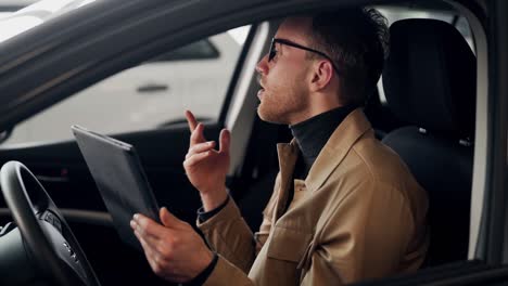 joven elegante hablando en el auto en video a través de una tableta