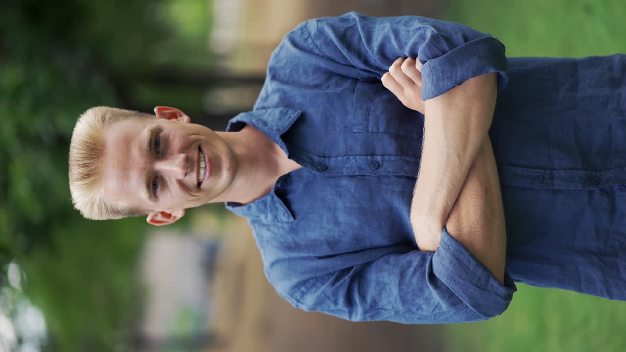 공원의 나무 사이에서 자연 속에 서서 긴장을 풀고 신선한 공기를 호흡하는 젊은 행복한 금발 남자의 클로즈업 초상화.