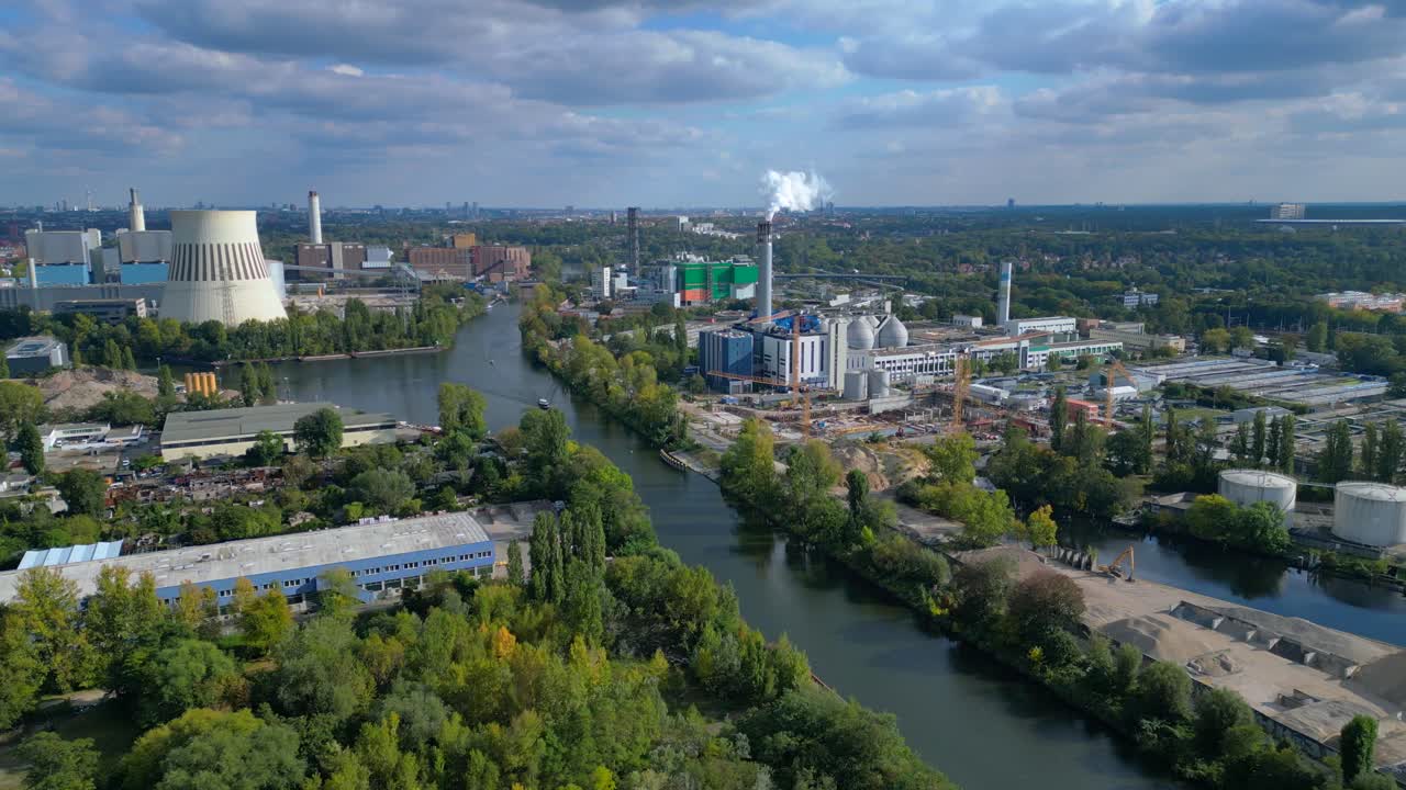 Industrial landscape with factories, a large power plant, and storage tanks bordering river in berlin germany. Majestic aerial view flight static tripod hovering drone