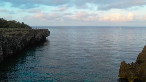 Cinematic-Aerial-view-of-Caribbean-reef-,-turquoise-water,-rocky-beach-during-sunrise,-Roatan-island,-west-end,-Honduras