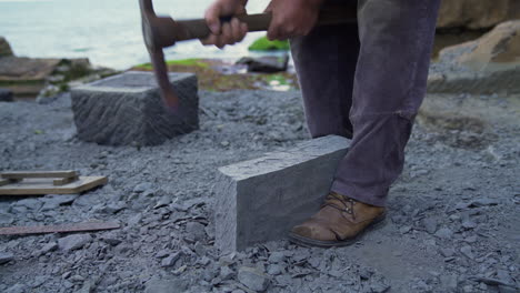 handheld shot of a master craftsman shaping a cancagua stone with a hand tool in the city of ancud of the shoreline of chiloe island