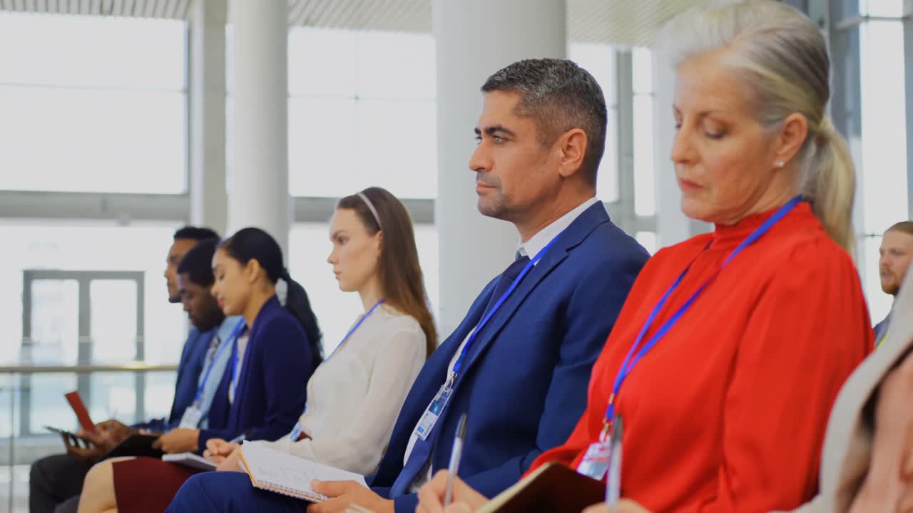 노트패드 에 글 을 쓰고 비즈니스 세미나 에 앉아 있는 사업가 들 4k