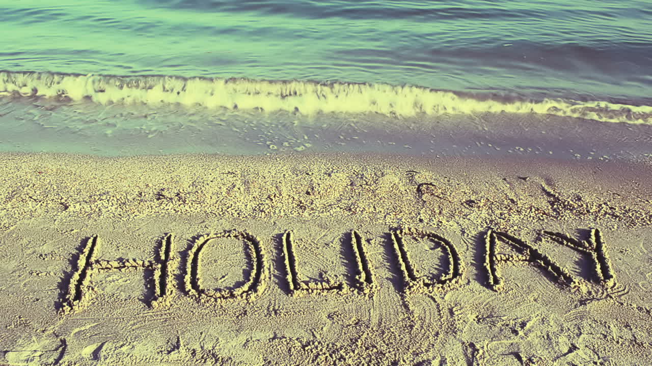 Indskriften "Holiday" i sandet på stranden. Optagelse på stranden