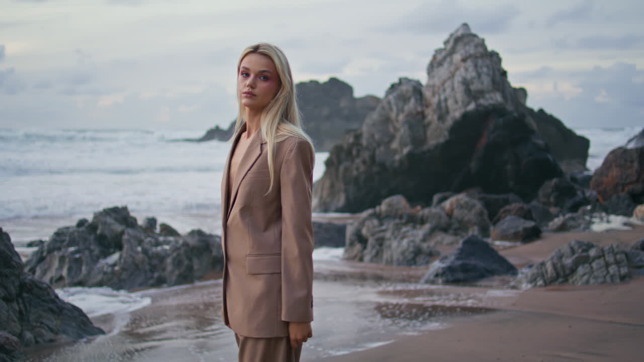 Pensive woman going seashore in fashionable suit. Pretty girl thinking walking