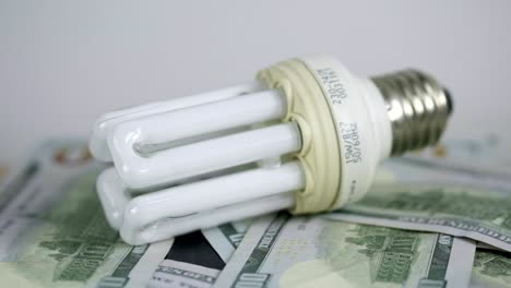 Light-bulb-rotate-on-100-usd-note-bills-Increase-in-electricity-tariffs-concept