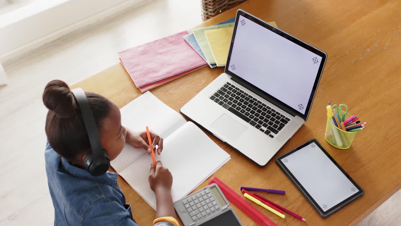 Unaltered african american girl using laptop and tablet with copy space in online class, slow motion