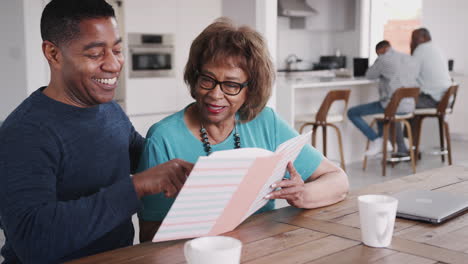 middle aged black man looking through a photo album with his mother at home, close up