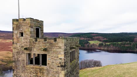 Old-derelict-castle,-monument,-disused-stone-tower,-with-people-walking-around-and-flying-a-drone