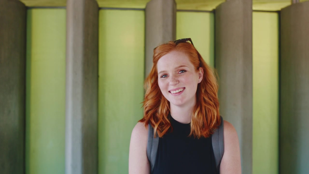 Smiling Young Woman with Red Hair Standing Outdoors