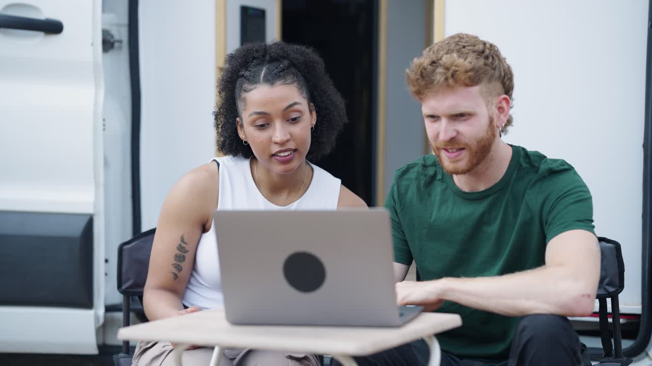 Couple working on laptop outside of van