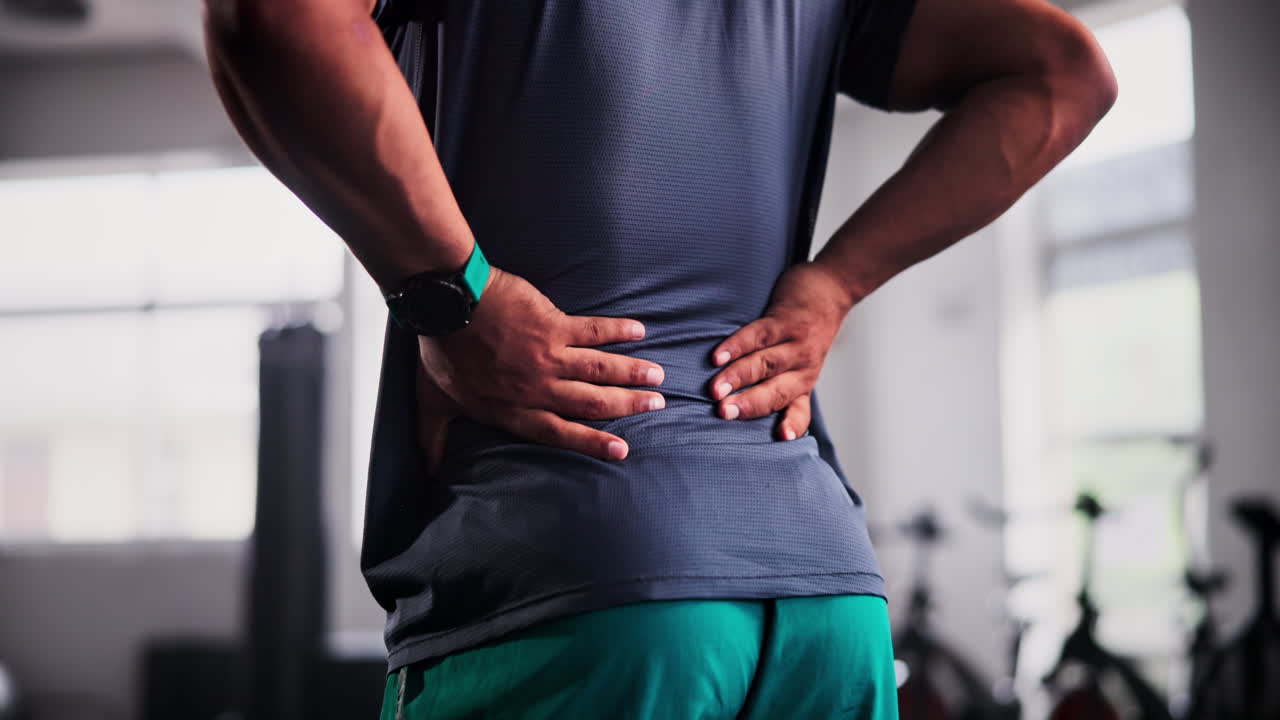 hombre con dolor de espalda en el gimnasio