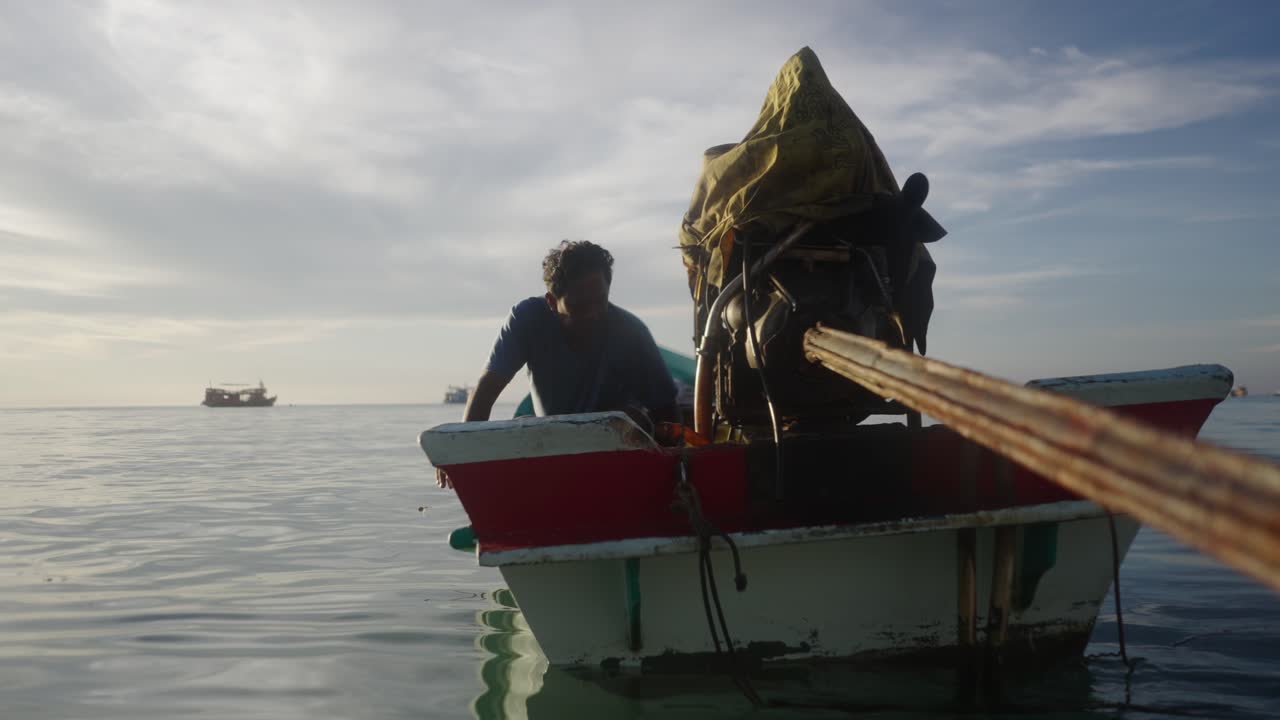 A man in a small boat on the water under a cloudy sky