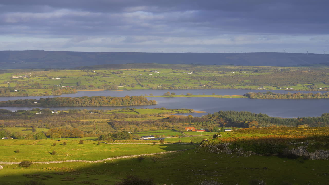 Tidsforløp av landlig jordbrukslandskap med åser og innsjø i det fjerne på en solrik, skyet dag, sett fra Carrowkeel i Sligo fylke i Irland