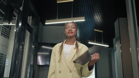 self-confident young african american female office worker portrait in modern interior of office