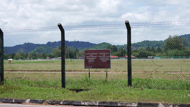Ampia vista di un campo d'aviazione aeroportuale ristretto in Malesia, protetto da recinzione perimetrale e un cartello di avvertimento di divieto di accesso, che illustra la sicurezza aerea, l'accesso controllato e la sicurezza della pista