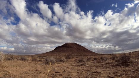 Clouds-roll-over-barren-Mojave-Desert-plain-with-single-mountain,-Time-Lapse