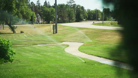 sprinklers watering grass in a park on a sunny day