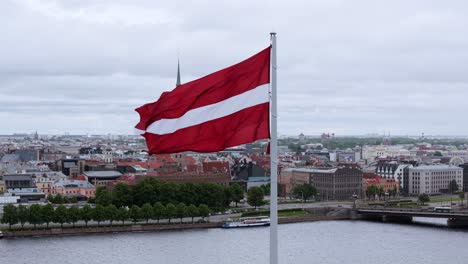 massive latvian flag flutters on cloudy day above riga with old town panorama