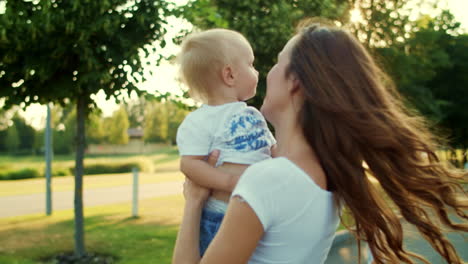 Mother-holding-son-on-hands-in-park