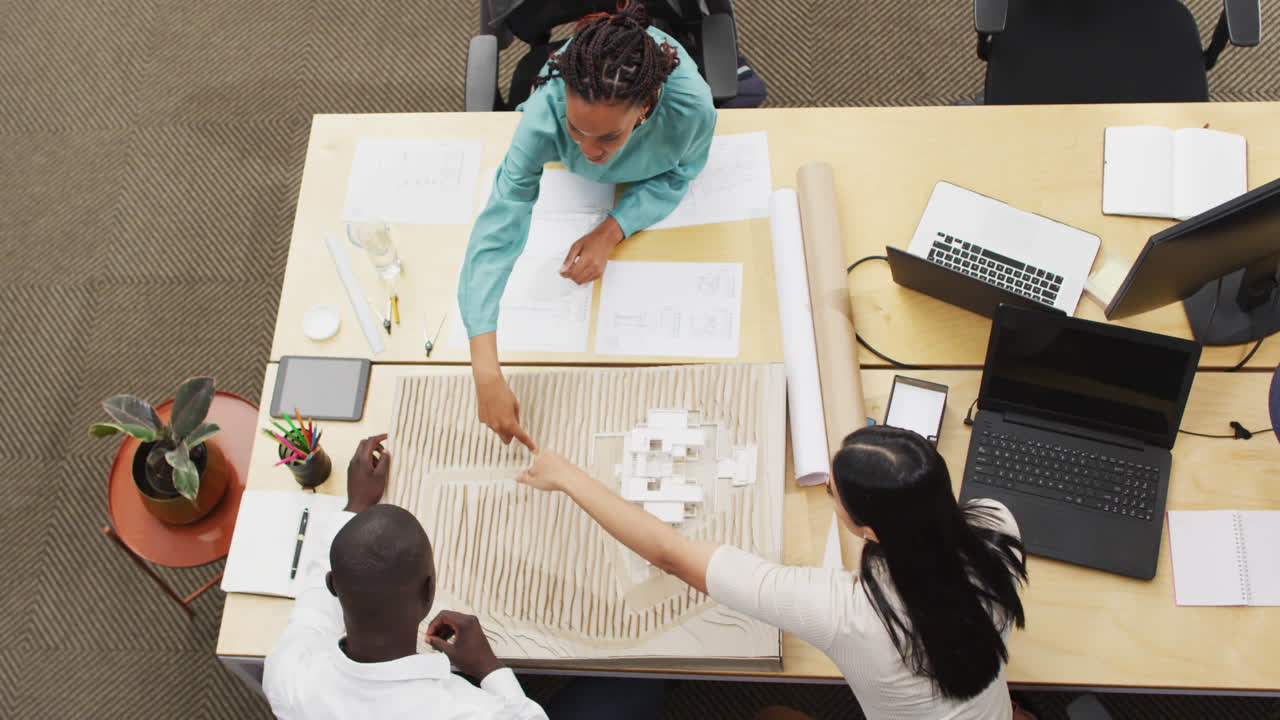 Happy diverse architects looking at architectural models at office