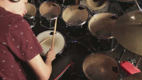 young talented drummer playing his drum set and practicing while using headset - close up shot