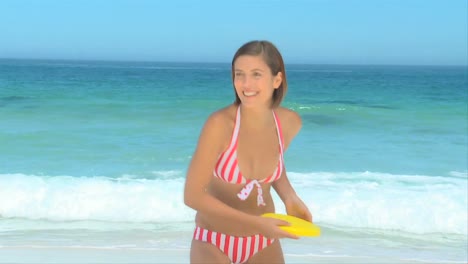 woman in a pink and white swimsuit playing frisbee