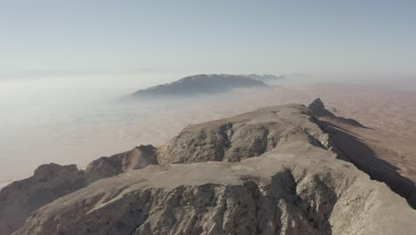 Captivating-aerial-view:-Morning-fog-over-Fossil-Rock,-Sharjah