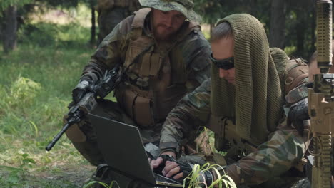 military men using laptop in jungle