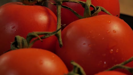 a slow motion close up shot of some tomatoes rotating, with some small water drops on their skin