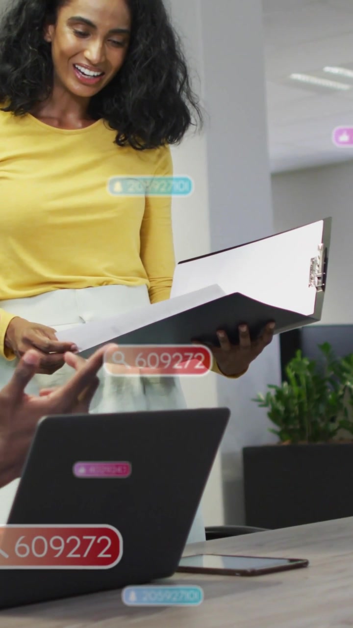 Video verticale: Donna che mostra un raccoglitore mentre un collega indica il laptop, con un'interfaccia utente sovrapposta che aiuta il business.