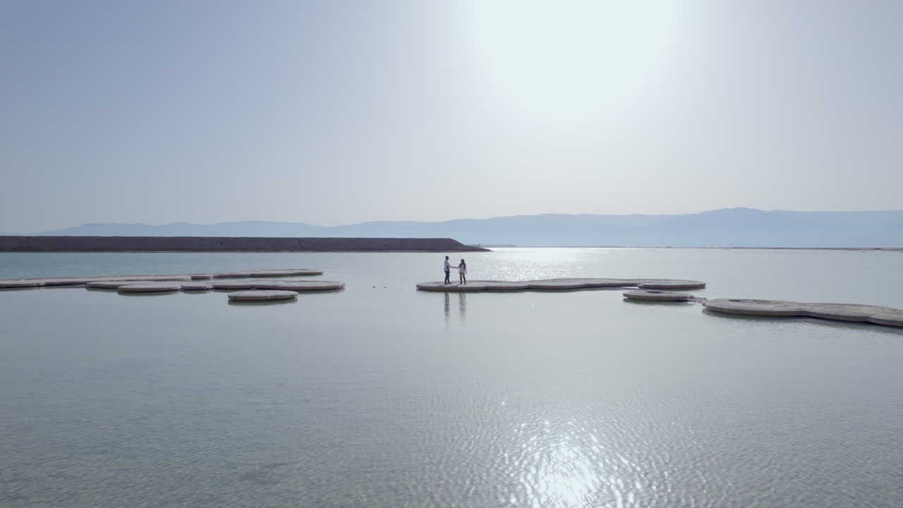 죽은 바다의 큰 소금 원 위에 서 있는 연인 부부