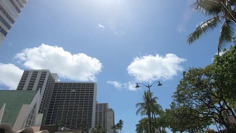 Driving-through-honolulu-waikiki-stop-signs-buildings-blue-sky-clouds-and-shops