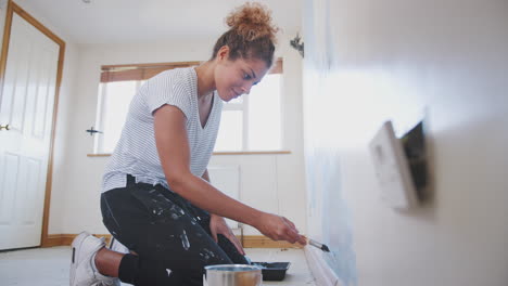 young woman decorating room in new home painting wall with brush