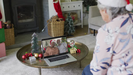 Mujer-Caucásica-Mayor-Usando-Una-Computadora-Portátil-Para-Una-Videollamada-Navideña-Con-Una-Pareja-Sonriente-En-La-Pantalla