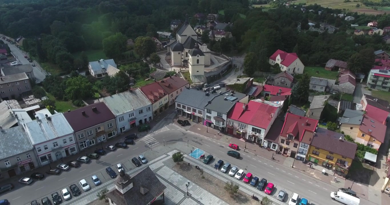 4K-dronekuva vanhasta kaupunginaukiosta Itä-Euroopassa, jossa on historiallinen kirkko ja autoja aurinkoisena kesäpäivänä.