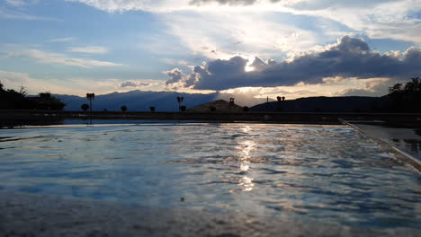 A-hand-splashing-The-calm-water-surface-of-an-infinity-pool-with-a-beautiful-mountain-view