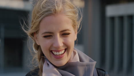 portrait happy young blonde woman student laughing running hand through hair enjoying successful lifestyle in city wind blowing hair