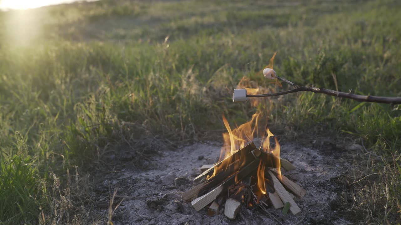 asando malvaviscos en una fogata en la playa al atardecer