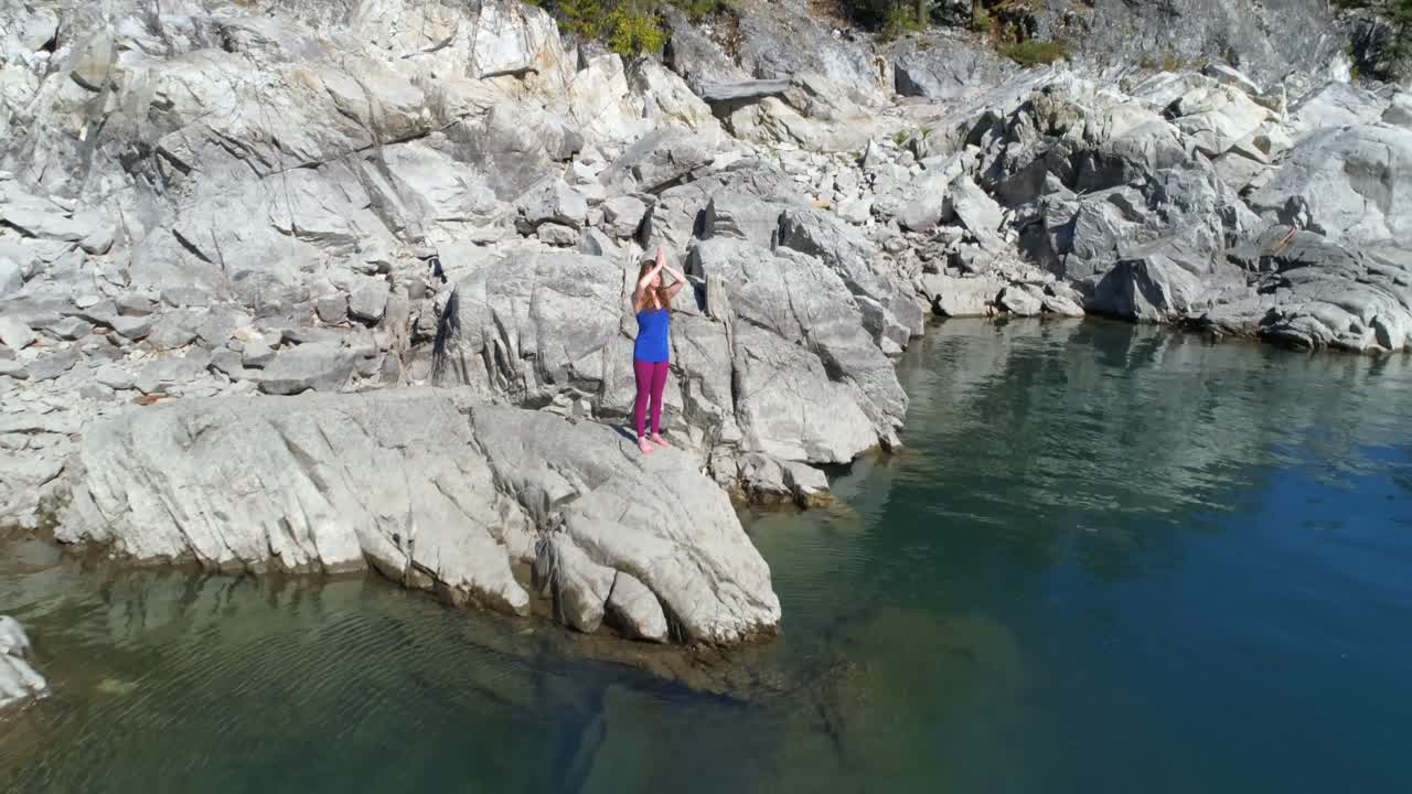 mujer realizando yoga en la orilla del lago 4k