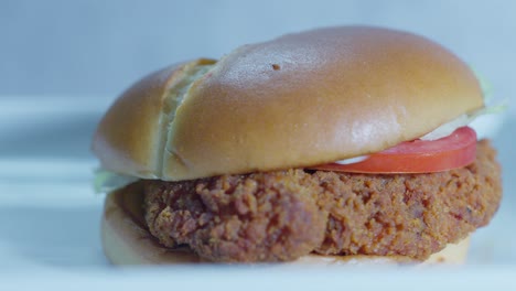 a delicious chicken sandwich sits on a plate, showcasing a crispy, golden fillet nestled between a soft bun with fresh lettuce, tomato, and savory condiments