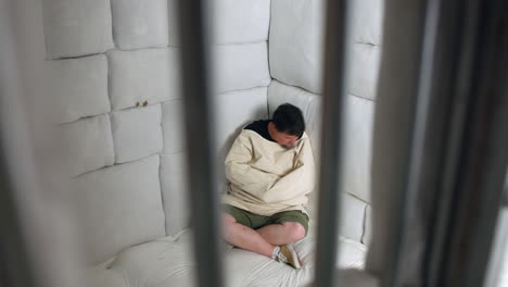 man in a straitjacket sitting in a padded room