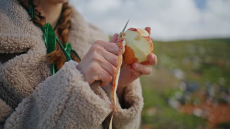 las manos pelando la piel de la manzana en el viaje de primer plano. mujer preparando un bocadillo saludable fresco
