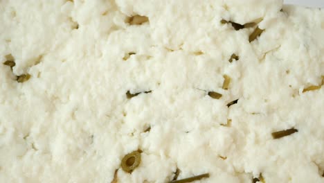close-up of sliced white cheese with pickled vegetables