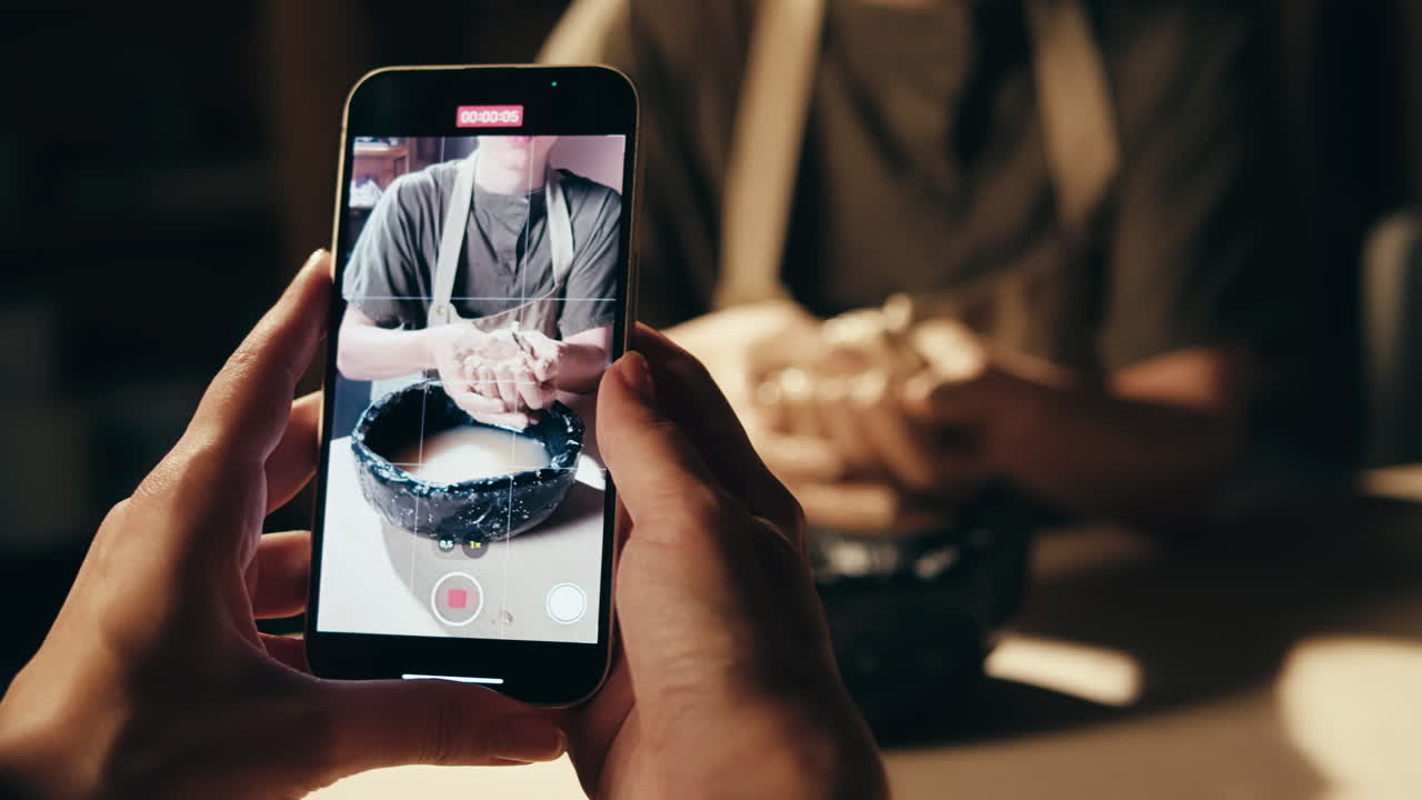 Person making pottery on a smartphone video