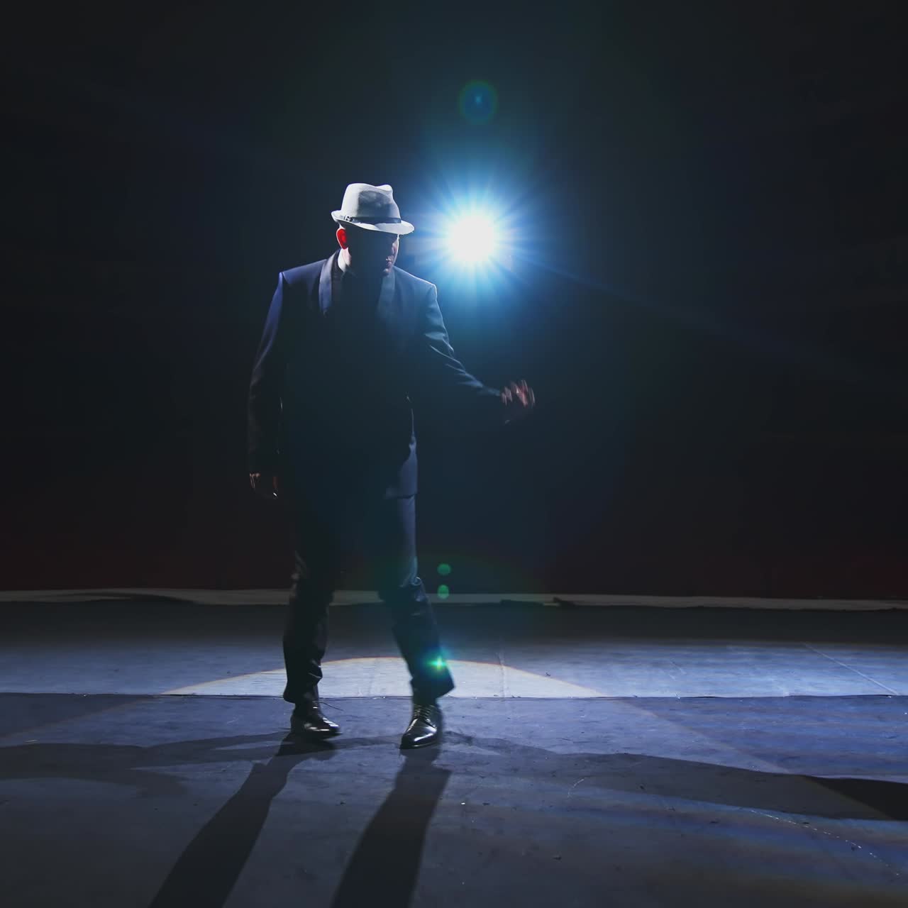 Artist dancing on scene. Theatrical man in elegant suit and hat performing on stage in spotlight. Entertainment concept.