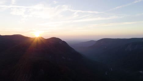 drone flying forward through mountain range at sunrise.