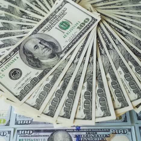 circle of one hundred dollar bills spinning. us dollars banknotes. rotational motion of cash on dollars background. close-up.