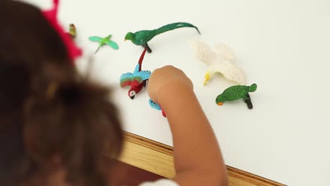 child playing with rubber animals in a classroom table