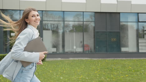 a girl in a business suit with a laptop in her hands running down the street against the backdrop of