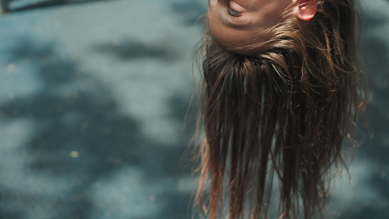 Dochter hangt ondersteboven op de speeltuin. Een close-up portret toont haar gevlochten haar dat door zonovergoten schaduwen zwaait, met een oprechte vreugdevolle uitdrukking. Het is een moment van zomers buitenspel en zorgeloze kindertijd.